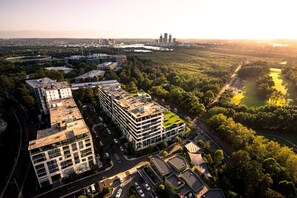 An aerial view of a modern urban area with multiple buildings, roads, and a river. - Sydney Olympic Park View Bliss | Modern Design (Sydney Olympic Park)