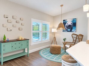 Una habitación con un mueble de almacenamiento color turquesa, un tapete redondo, muebles de mimbre y una pared con citas motivacionales.