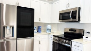 Une cuisine moderne dotée d’appareils électroménagers en acier inoxydable, de meubles blancs et d’un four encastré.