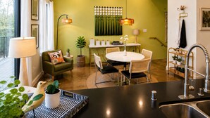 A modern kitchen with a dining area, featuring a round table, chairs, a black countertop, and a sink.