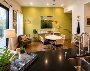 A modern kitchen with a dining area, featuring a round table, chairs, a black countertop, and a sink.