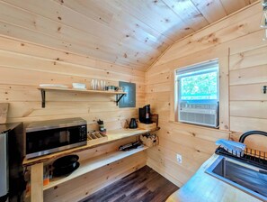 A compact kitchen with wooden walls, a microwave, a coffee maker, and a window with a view of greenery. - Cabin at the lake, Free Kayaks, Hiking & Fishing (Franklin)