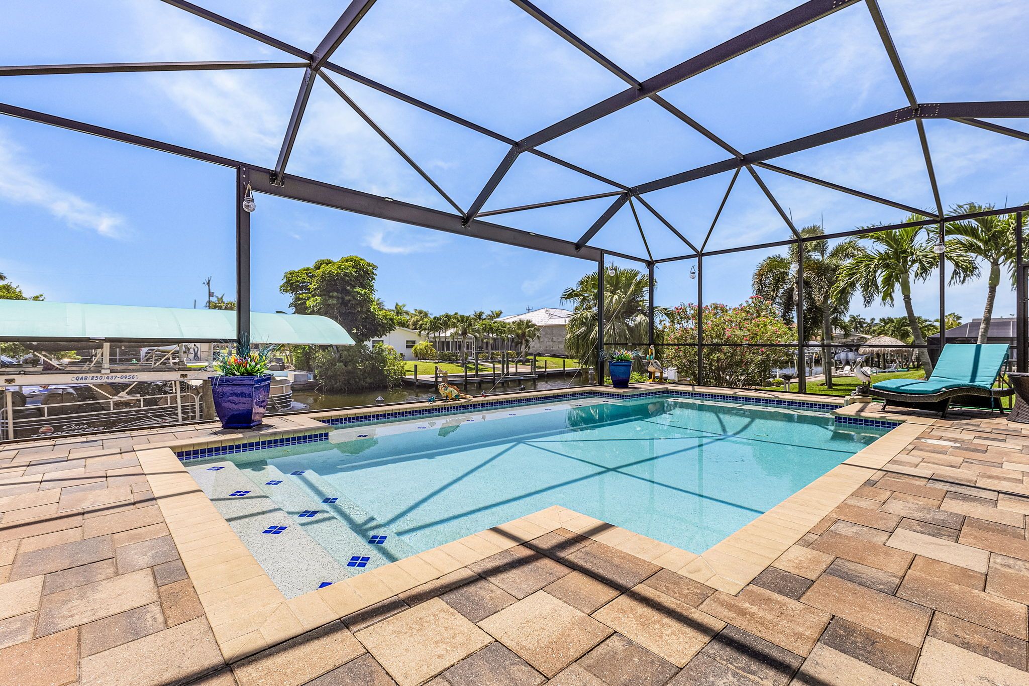 An indoor swimming pool with a clear view of the surrounding area, including palm trees and a building in the background.