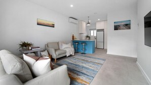 Ein modernes Wohnzimmer mit einer Couch, einem Couchtisch und einer blauen Barinsel mit Barhocker.
