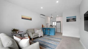 A modern living room with a sofa, a coffee table, and a blue island with bar stools.