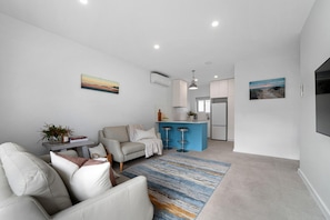 Uma sala de estar moderna com um sofá, uma mesa de centro e uma ilha azul com banquetas.