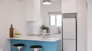 A modern kitchen with a blue island, stainless steel appliances, and a hanging light fixture.