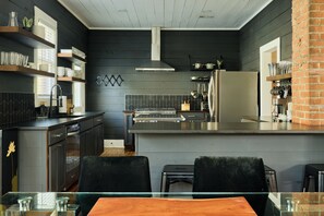 A modern kitchen with dark wood paneling, a stainless steel island, and a brick accent wall.