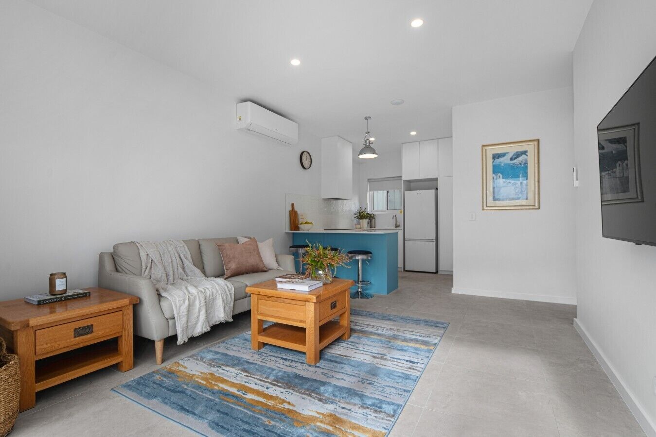 A modern living room with a sofa, coffee table, and a kitchen area in the background.