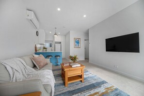 A modern living room with a sofa, coffee table, and a kitchen area in the background.
