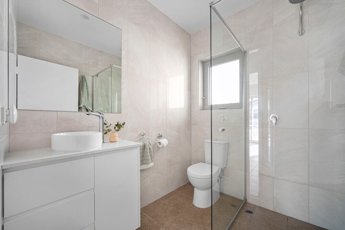 A modern bathroom with a glass-enclosed shower, a white sink, and a toilet.
