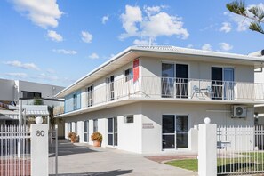 A modern building with a gated entrance, numbered 80, and a balcony with a railing. - Esplanade Apartments | Ocean View Beachfront | West Beach (West Beach)