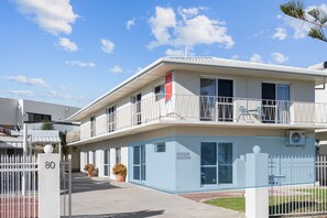 Ein zweistöckiges Gebäude mit Balkon, einem vergitterten Eingang und einem Schild, das auf Geschäfts- oder Büroflächen hinweist.