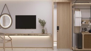 Un hall d’hôtel moderne doté d’un téléviseur à écran plat, d’un grand miroir rond, d’un comptoir d’accueil et d’un espace salon.