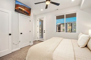A bedroom with a bed, a ceiling fan, a TV mounted on the wall, and a window with blinds. - Desert Haven, Private Spa, Community Amenities w/ Water Slide (Hurricane)