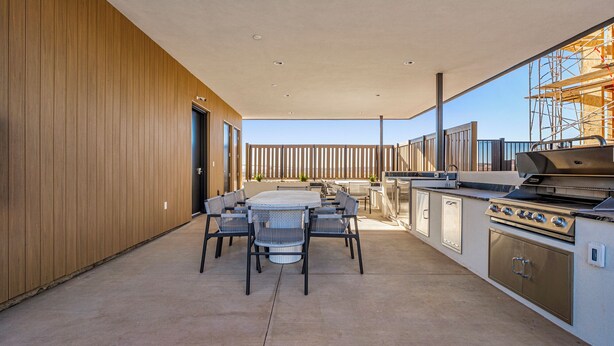 A modern outdoor kitchen with a grill, dining area, and wooden paneling. - Desert Haven, Private Spa, Community Amenities w/ Water Slide (Hurricane)