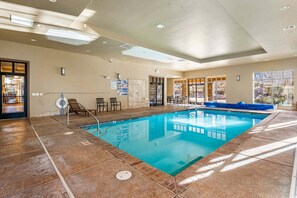 An indoor swimming pool with clear water, surrounded by a tiled floor, and equipped with safety railings. - Desert Haven, Private Spa, Community Amenities w/ Water Slide (Hurricane)