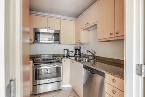 A compact kitchen with stainless steel appliances, a microwave, a coffee maker, and a dishwasher. - Blueground | Fenway–Kenmore, fitness, nr Fenway Park (Boston)