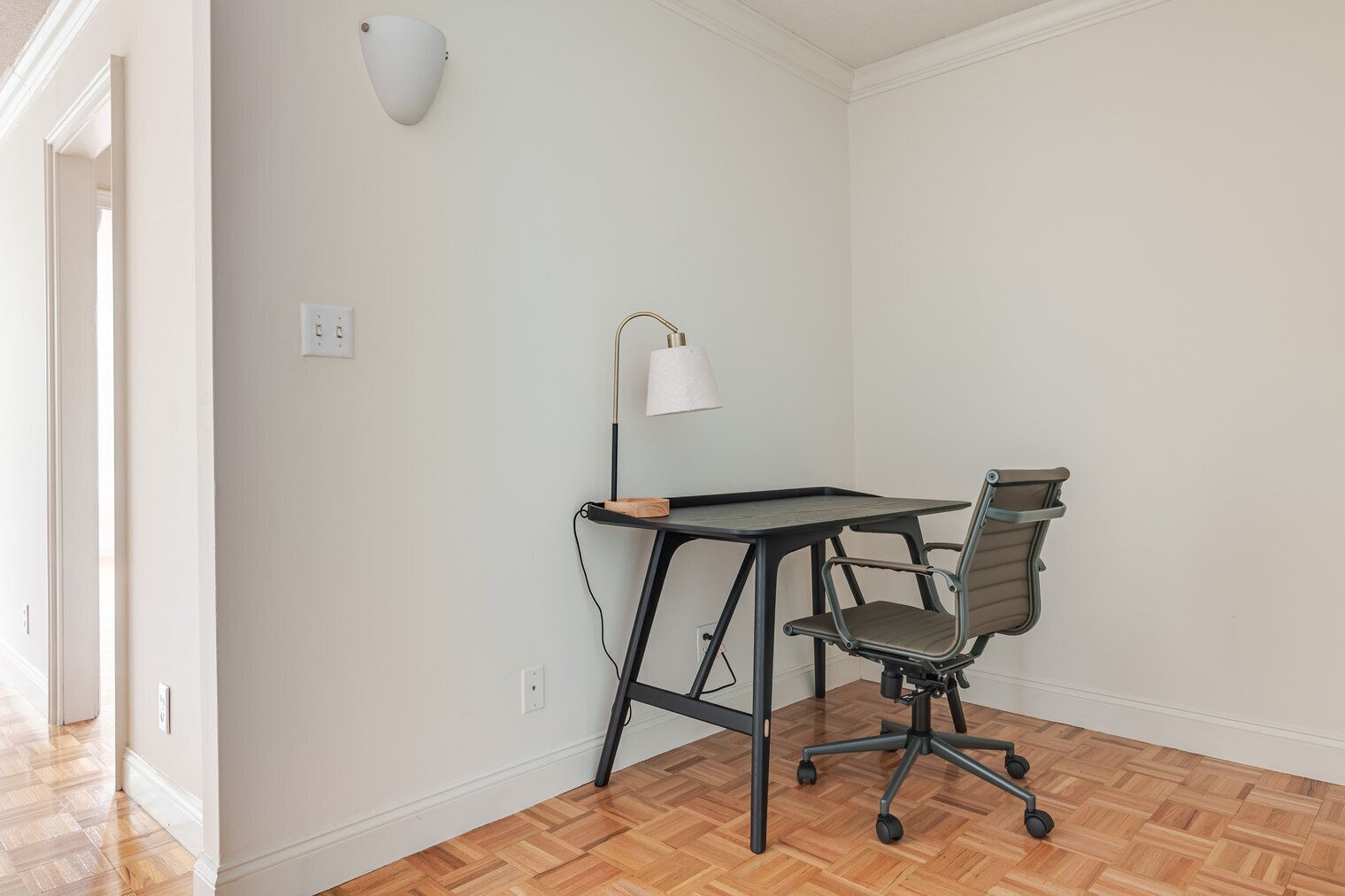 Une pièce comprenant un bureau, une chaise, une lampe et un interrupteur sur le mur.