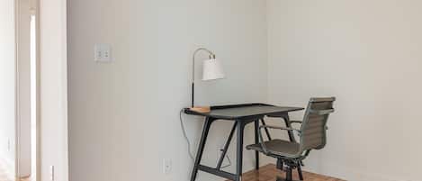 Una stanza con una scrivania, una sedia, una lampada e un interruttore a muro.