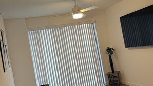A living room with a ceiling fan, a sofa, a small table with a vase, and a window with blinds. - Cozy 1-bedroom apartment in pleasant Hollywood  Downtown ,pool and gym access. (Hollywood)