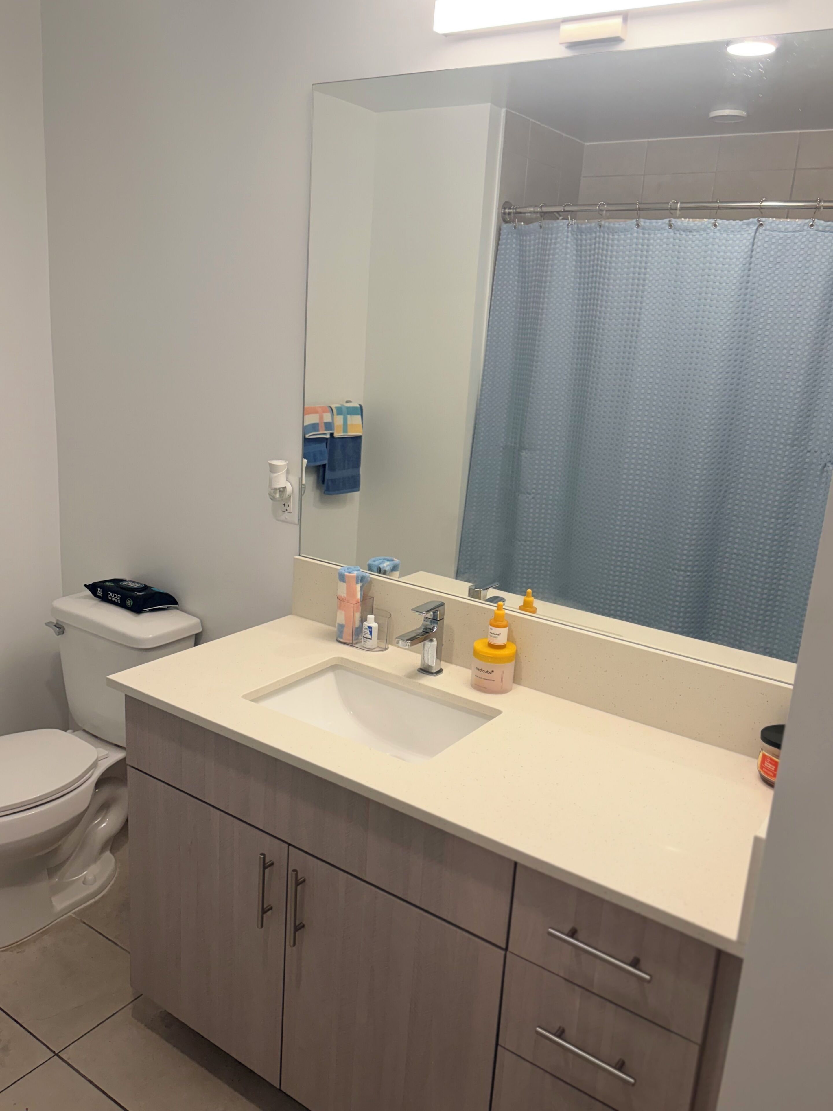 A bathroom with a white sink, a mirror, a toilet, and a shower curtain.