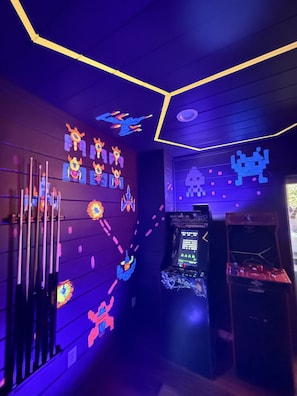 A room with a retro arcade machine, neon lights, and a wall with colorful, pixelated designs. - Indoor Pool, Arcade, Theater, Hot Tub, 50% off Zipline (Sevierville)