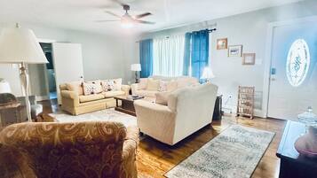 Una sala de estar con un sofá, un sillón estampado, una mesa de centro y una alfombra.