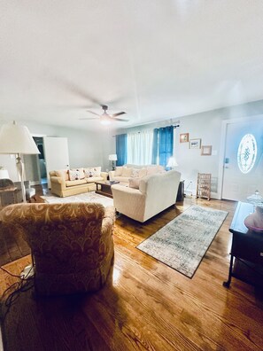 A living room with a sofa set, a patterned armchair, a coffee table, and a rug. - 4BR/3BTH Home in Eden, NC -Near Berry Hill Megasite & Martinsville Speedway (Eden)