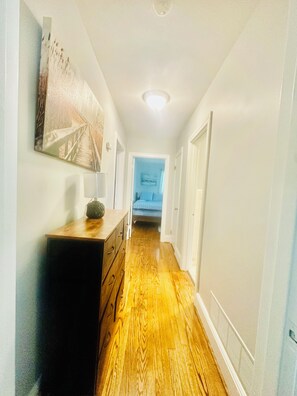 A hallway with wooden flooring, a dresser, and a painting on the wall. - 4BR/3BTH Home in Eden, NC -Near Berry Hill Megasite & Martinsville Speedway (Eden)