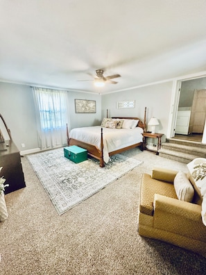 A bedroom with a bed, a nightstand, a lamp, a chair, a suitcase, and a ceiling fan. - 4BR/3BTH Home in Eden, NC -Near Berry Hill Megasite & Martinsville Speedway (Eden)
