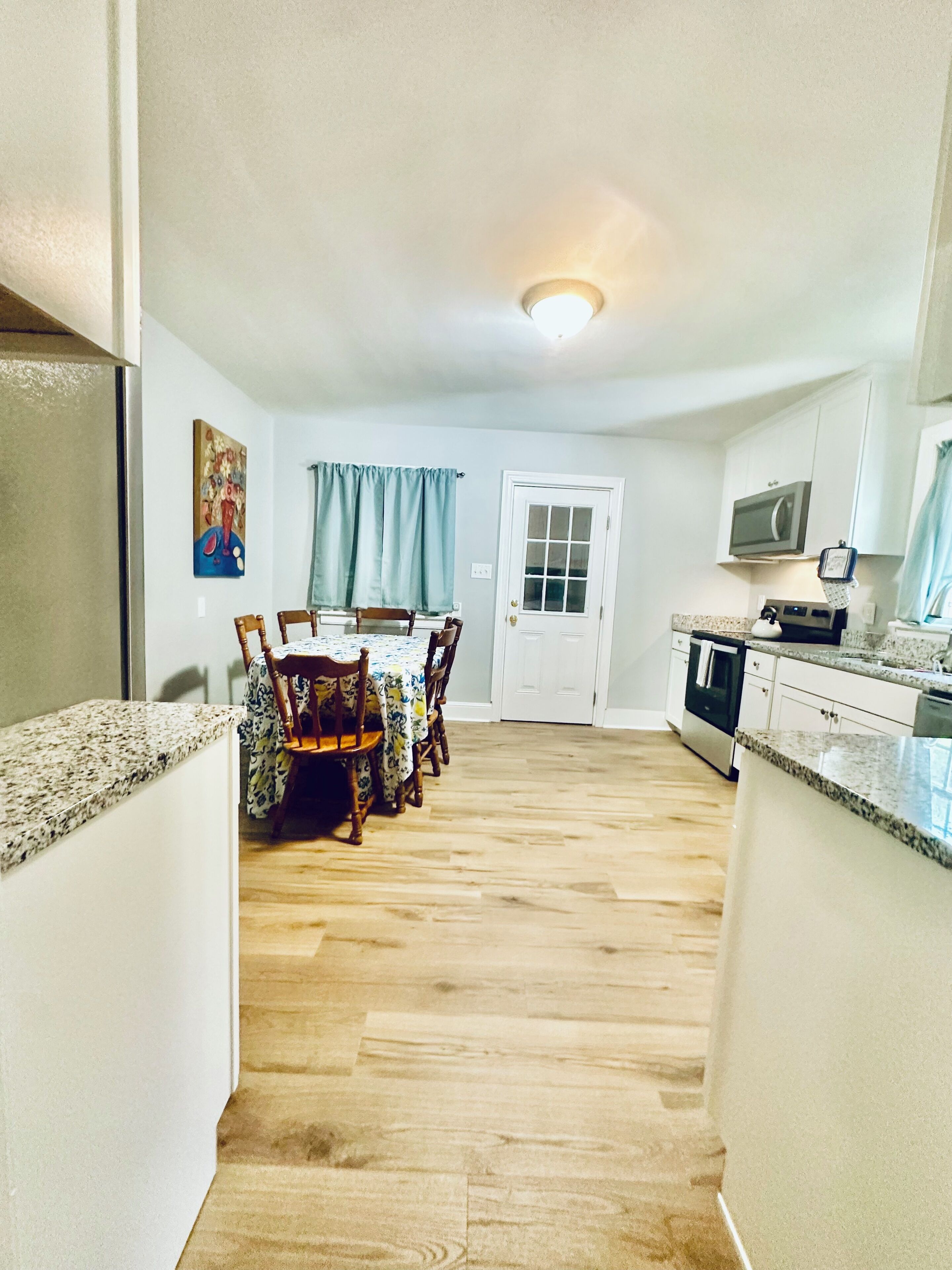 A kitchen with a dining area, wooden chairs, a table, and a door.