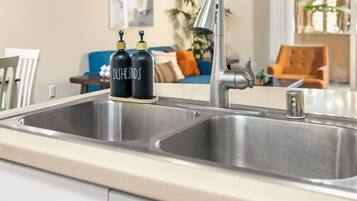 A kitchen with a double sink, two black soap dispensers, and a modern faucet.