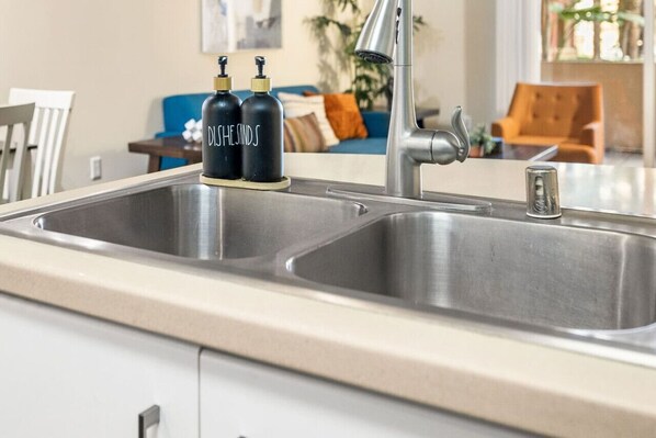 A kitchen with a double sink, two black soap dispensers, and a modern faucet.