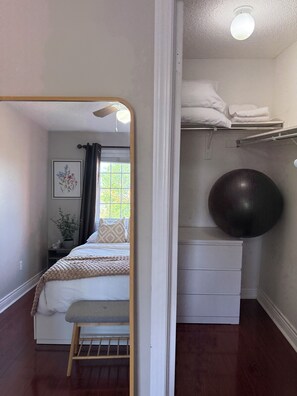 A bedroom with a bed, a bench, a mirror, a window with curtains, a plant, and a storage unit with a round exercise ball. - Beautiful 3BR semi detached (entire) home in Brampton (Brampton)