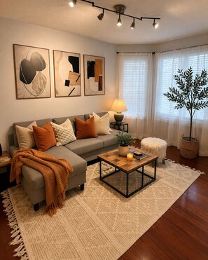 Ein Wohnzimmer mit Sofa, Couchtisch, Lampe und Bildern an der Wand.