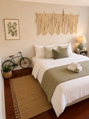 A neatly arranged bedroom with a bed, pillows, a bedside lamp, a framed plant, a bicycle, and a macramé wall hanging. - Beautiful 3BR semi detached (entire) home in Brampton (Brampton)