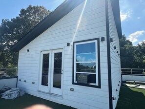A white building with a black roof, a large window, and a door.