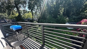 A wooden deck with a metal railing, a table, and a chair.