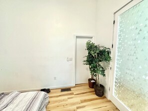 A bedroom with a bed, a potted plant, and a door.