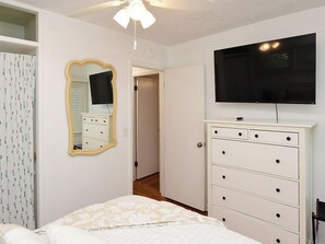 Un dormitorio con cama, cómoda, espejo y televisor.