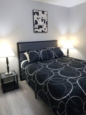 A bedroom with a bed, two bedside tables, a wall-mounted artwork, and a floor lamp. - 2 Condos Adjacent - for groups  4-Night DISCOUNT!! (Branson)
