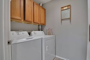 A laundry room with two stacked washers and dryers, wooden cabinets above, and a window with blinds. - 2 Condos Adjacent - for groups  4-Night DISCOUNT!! (Branson)