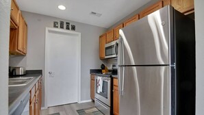 A kitchen with stainless steel appliances, wooden cabinets, a microwave, and a tiled backsplash. - 2 Condos Adjacent - for groups  4-Night DISCOUNT!! (Branson)
