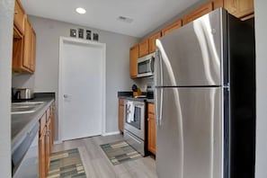 A kitchen with stainless steel appliances, wooden cabinets, a microwave, and a tiled backsplash. - 2 Condos Adjacent - for groups  4-Night DISCOUNT!! (Branson)