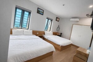 Habitación de hotel con dos camas, un armario y ventana con vistas.