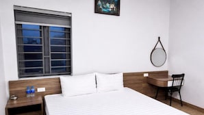 A hotel room with a bed, a desk, a chair, a window, and a painting on the wall. - Hung Phat Hotel Nghe An  (Hung Nguyen)
