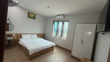 A bedroom with a bed, a wardrobe, a window with a view, and a wall-mounted air conditioner.