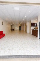 Un hall espacioso con mostrador de recepción, un sofá rojo y suelo estampado.