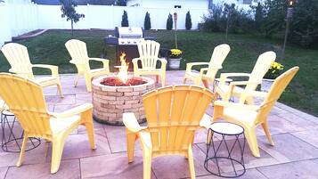 A patio with yellow Adirondack chairs arranged around a fire pit.